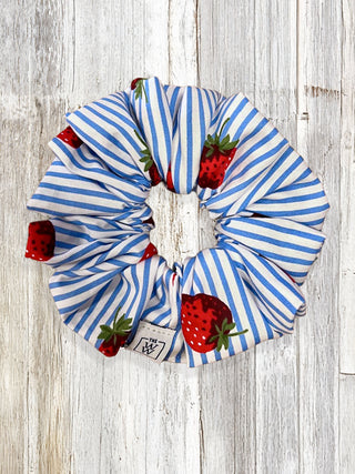 Blue and white striped scrunchie with strawberry pattern on a wooden background
