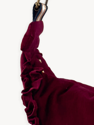 Close-up of a burgundy ruffled bag with a gold zipper on a white background