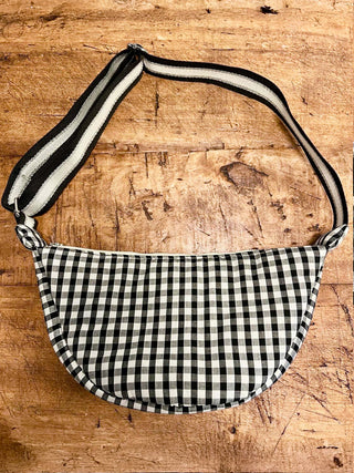 Black and white checkered bag with striped strap on a wooden surface