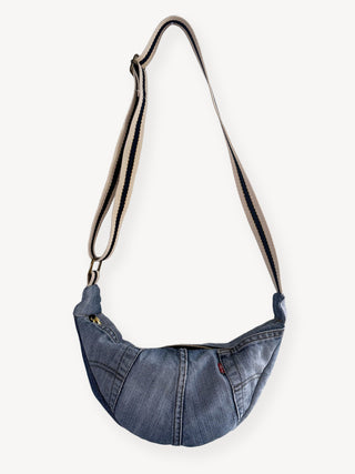 Denim cross body bag with a strap on a white background