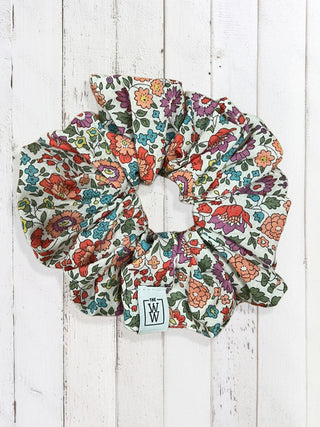 Floral scrunchie with a visible brand logo on a wooden surface