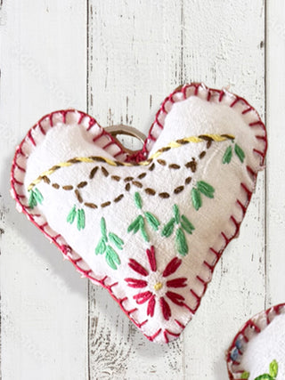 Heart-shaped embroidered keychain on a white wooden background