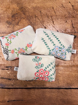 Three floral-patterned pouches on a wooden surface