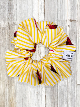 Yellow and white striped scrunchie with red accents on a wooden surface