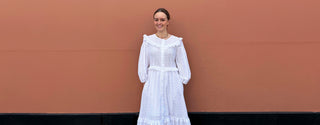 Model wearing bestselling white broderie vintage-inspired dresse by The Well Worn, made to order in the UK