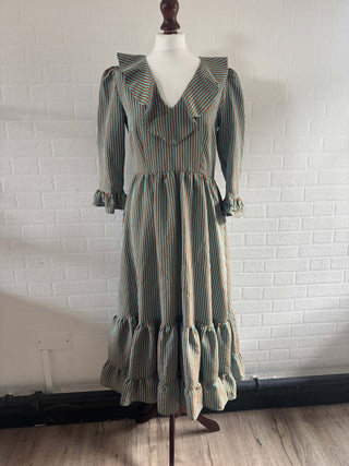 Vintage dress on a mannequin against a white brick wall.