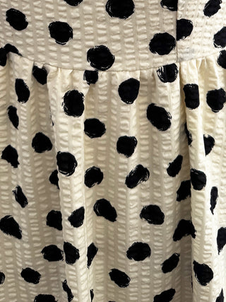 Close-up of a textured fabric with a black and off-white polka dot pattern.