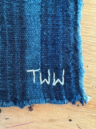 Blue fabric with 'TWW' embroidery on a wooden surface