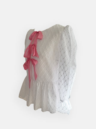 White lace top with pink bows on a white background