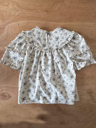 Floral blouse with ruffled sleeves on a wooden surface