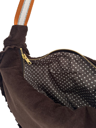 Close-up of a brown bag with a polka dot interior and gold zipper.