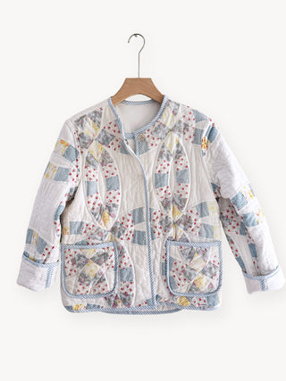 Patchwork jacket with floral patterns on a hanger against a white background