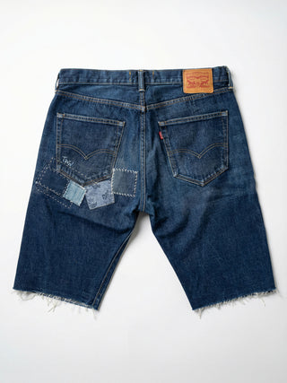 Back view of blue denim shorts with patchwork design on a white background
