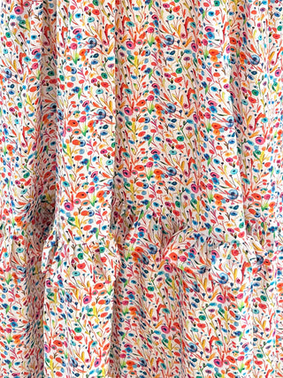 The Felicity Cotton Dress in bright floral Rainbow Meadow print, perfect for everyday wear with a flattering fit and playful ruffle details.