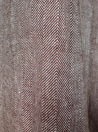 Close-up of a fabric with a herringbone pattern in burgundy and beige tones.