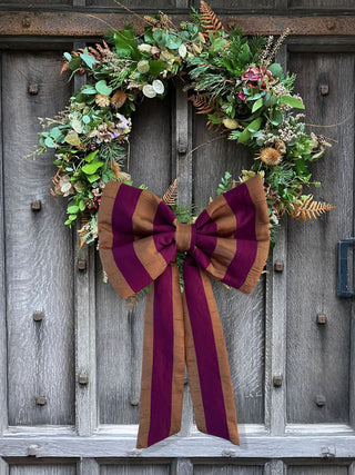 Decorative wreath with a large bow on a wooden door