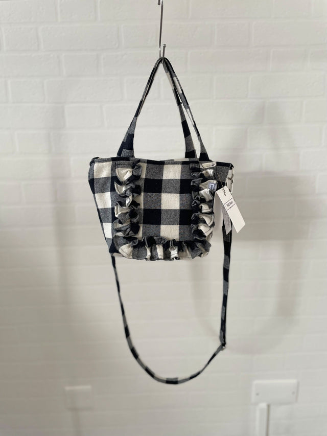 The Well Worn gingham tote hanging by wall with ruffle