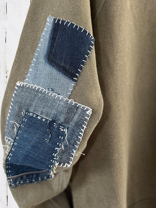 Close-up of a brown coat with denim patchwork on a white background