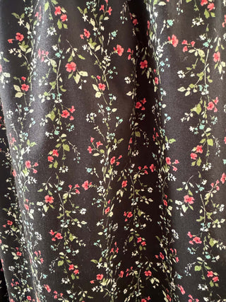 Floral patterned fabric with red, green, and white flowers on a black background