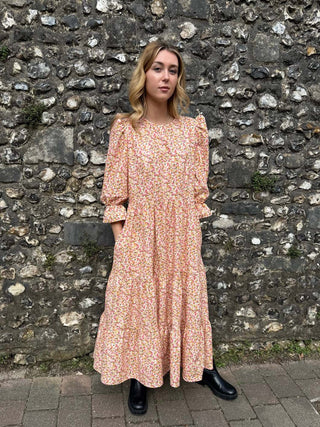 Ethical fashion – Model in The Grace Dress, featuring a tiered skirt, puff sleeves, and frill cuffs, made from sustainable deadstock cotton.