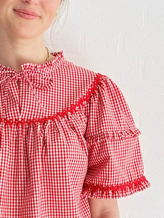 Sustainable fashion model wears the Lucy Top, made from deadstock red gingham, featuring oversized sleeves and self-fabric ties with denim