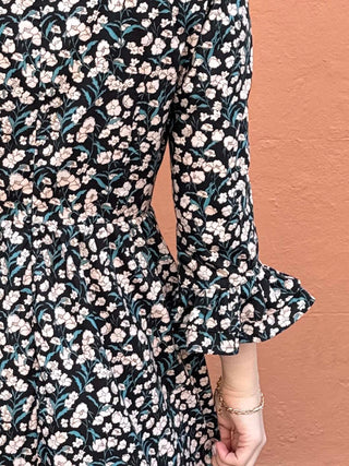 Ethically made UK floral midi dress featuring soft pink blossoms on a black background with gathered details.