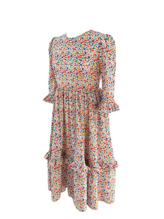 Side view of The Felicity Dress in Rainbow Meadow print, featuring a full skirt, side seam pockets, and gathered 3/4 sleeves with double ruffles.