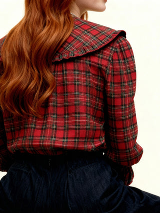 Person wearing a red plaid shirt with a high collar on a plain background