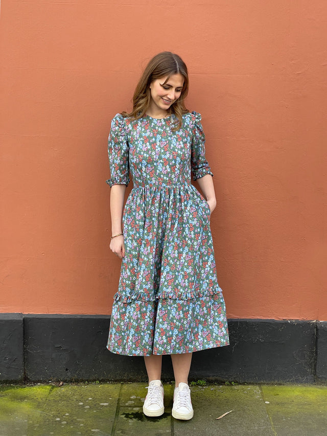 The Well Worn women wearing cotton floral dress with pocketsby wall
