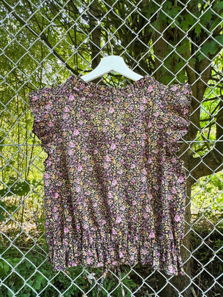 back floral print blouse on white hanger on chain link fence