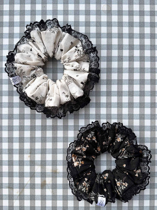 Two floral lace scrunchies, one black and white and one black, on a white background.
