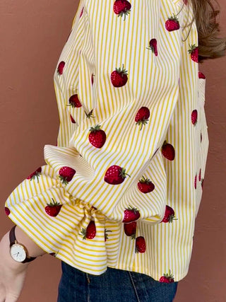 Detail shot of oversized puff sleeves and strawberry motif on striped cotton fabric.