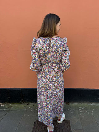 Back view of floral midi dress showing subtle V-neck opening with tie detail and gathered waist.