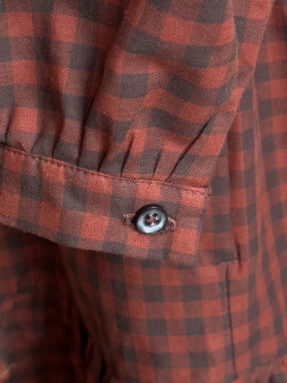 Close-up of a red and black checkered shirt with a button.