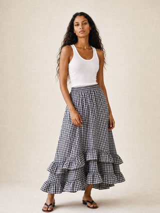 Woman wearing a white tank top and black and white checkered skirt on a beige background