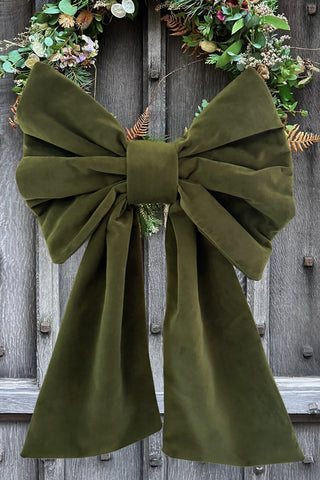 Large green bow on a wooden door with wreaths.