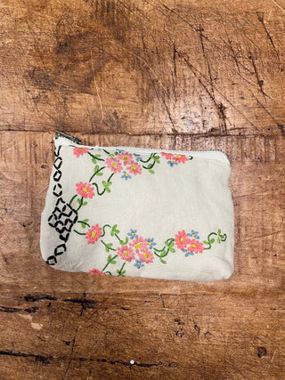 Embroidered pouch with floral design on a wooden surface