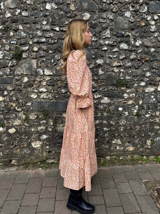 Side view of model in The Grace Dress – eco-friendly midi dress with a flowing tiered skirt and flattering bodice.