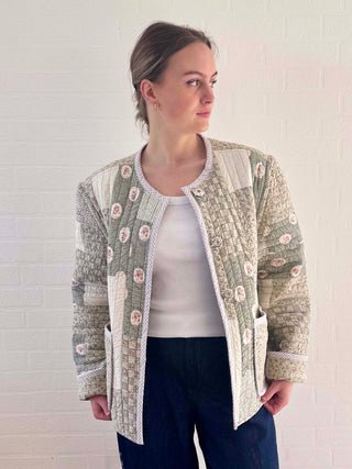 Model wearing a handmade reversible jacket in soft green tones, made from a vintage quilt and finished with bound seams and patch pockets