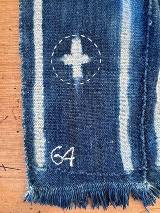 Close-up of a blue denim fabric with white stitching on a wooden surface