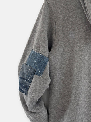 Gray sweatshirt with a denim patch on the sleeve against a white background