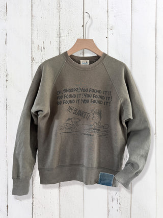 Gray sweatshirt with text and graphic on a wooden hanger against a white wooden panel background