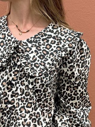 Leopard print blouse with ruffled collar on a plain background