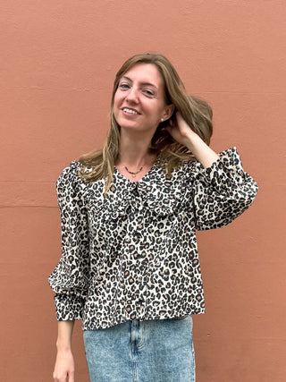 Woman wearing a leopard print blouse against a brown wall