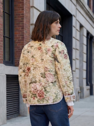 Woman wearing a floral jacket standing on a city street.