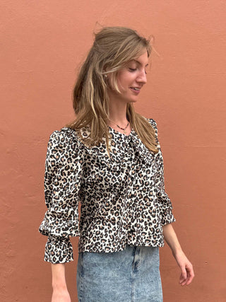 Woman wearing a leopard print blouse against a brown wall