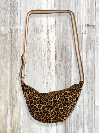 Leopard print bag with brown strap on a wooden surface