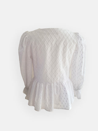 White textured blouse with ruffled hem on a light gray background