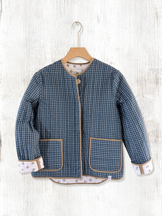 Blue checkered jacket on a hanger against a white wooden background