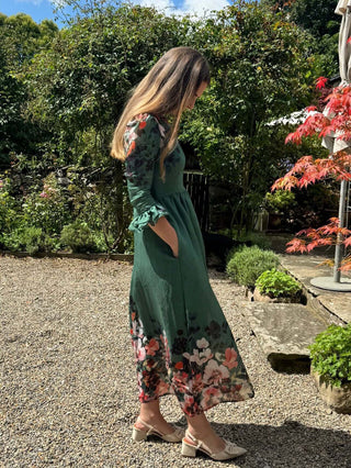 Woman in a green floral dress standing in a garden